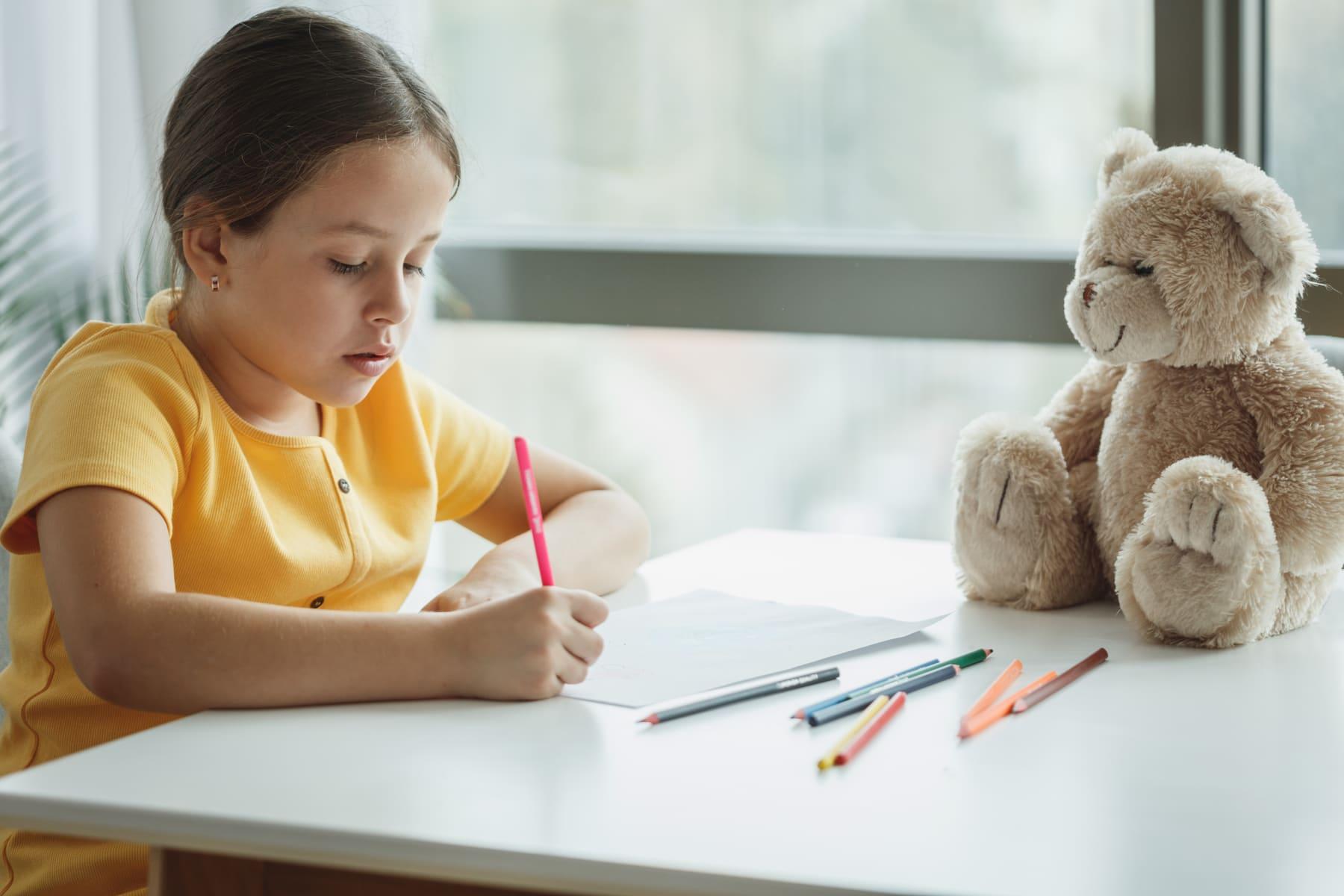 Une élève de primaire fait ses exercices au crayon, assise à une table